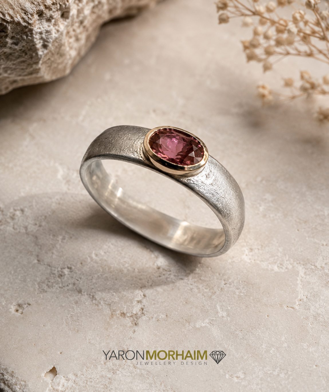 Aurora Tourmaline Ring with natural pink tourmaline gemstone displayed on a warm marble surface, handcrafted in sterling silver and 9-carat gold.