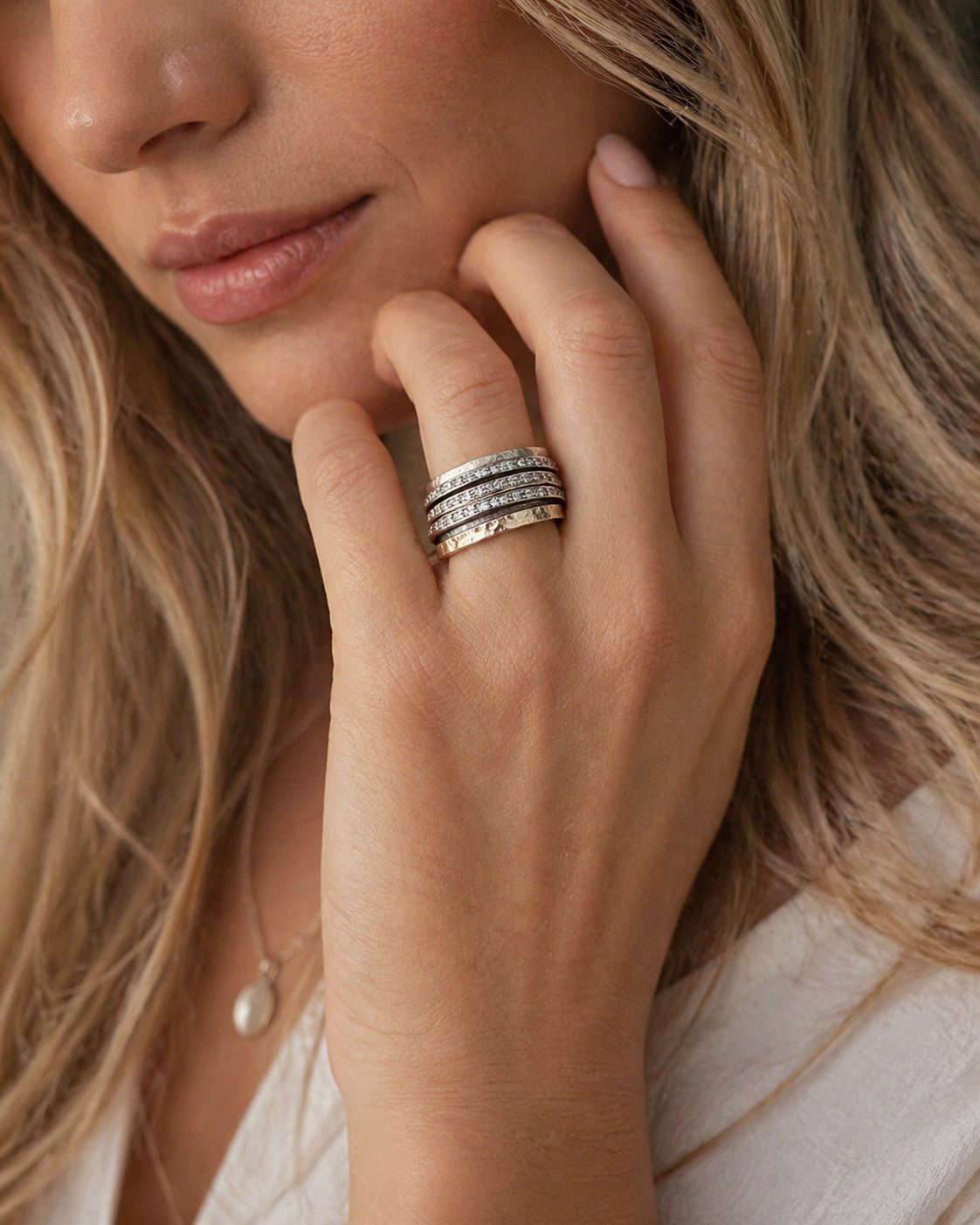 Handcrafted sterling silver spinning ring with 9ct gold rotating bands and cubic zirconia, worn by a stylish male model in a luxury close-up.